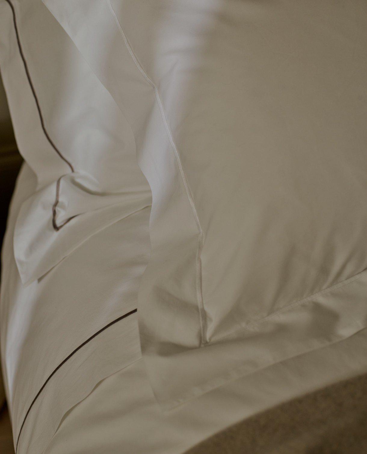 a close up of a bed with a white comforter and pillows